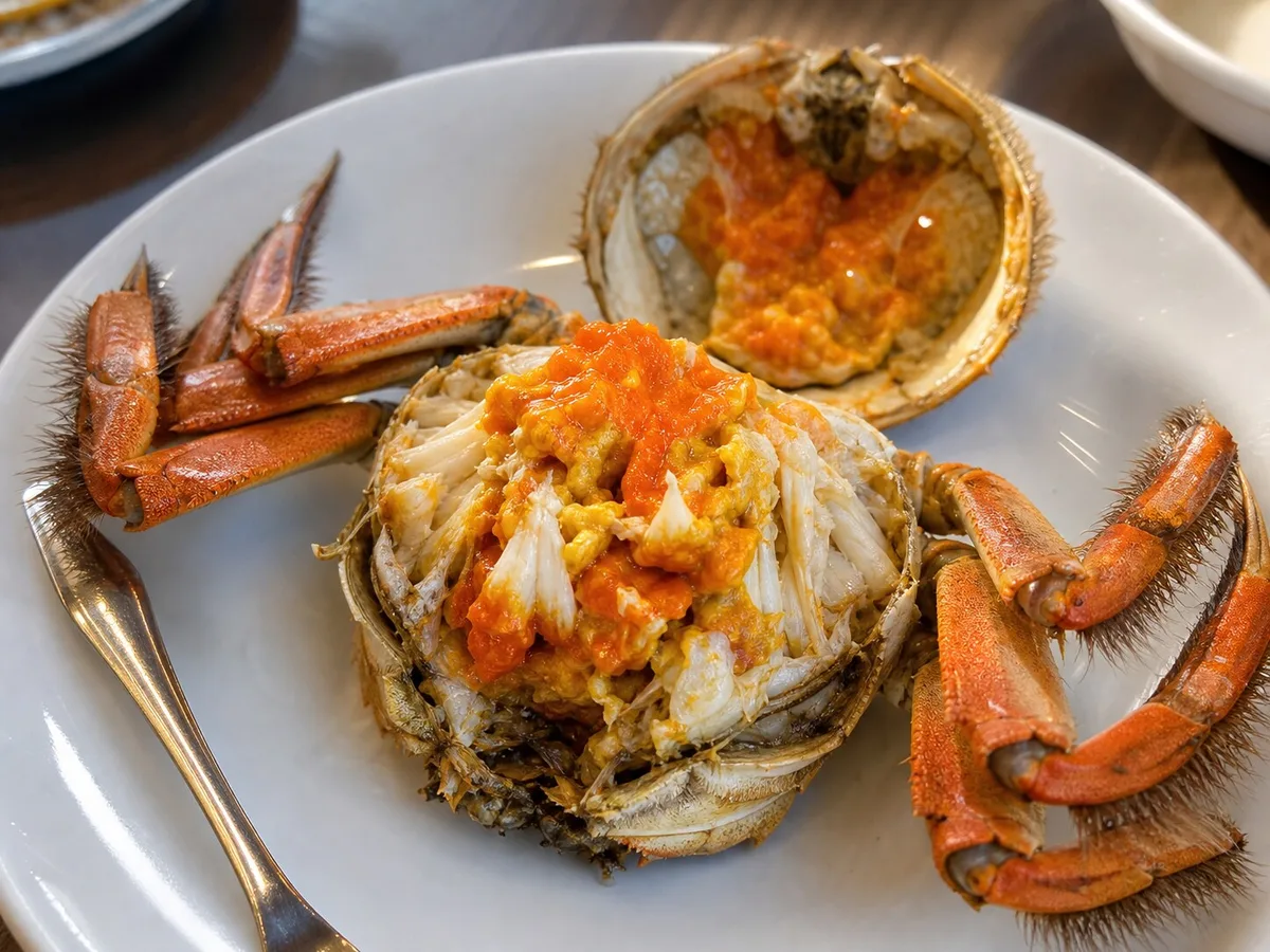 Opened Shanghai hairy crab showing orange roe and white crab meat on a plate