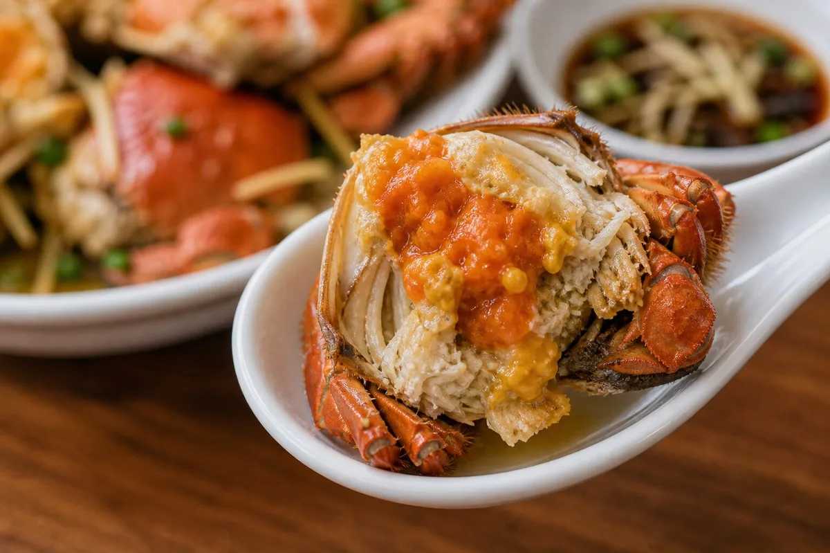 Opened Liuyuehuang young hairy crab on a spoon showing soft roe and tender meat