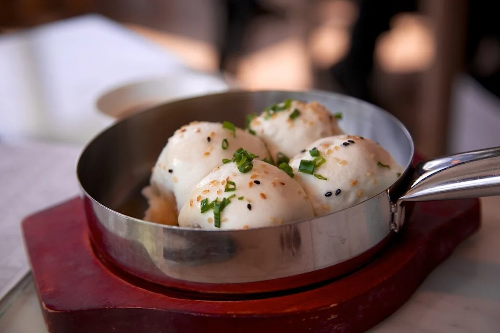 Pan of shengjian mantou showing browned pan-fried bottoms