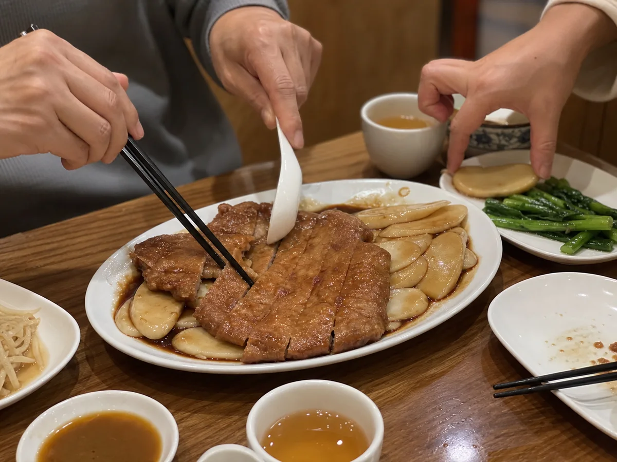 Two diners sharing Shanghai paigu niangao with pork chop, oval rice cakes, and leafy greens