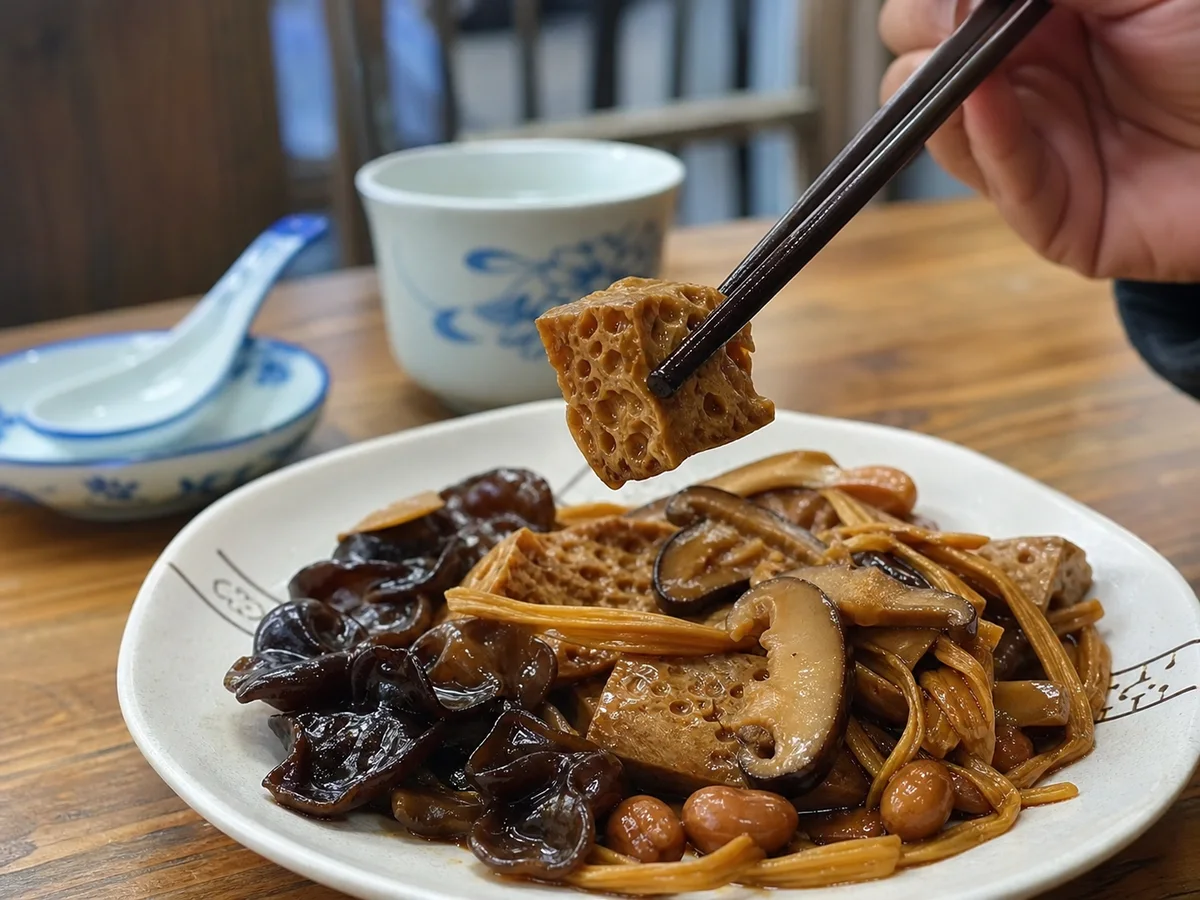 Diner lifting a porous braised wheat gluten cube from a Shanghai kaofu cold appetizer plate