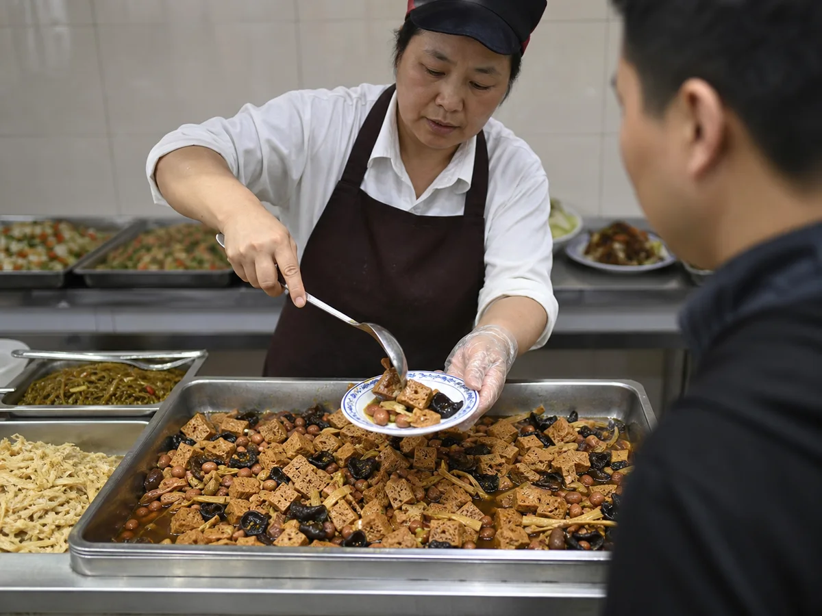Worker serving Shanghai sixi kaofu from a cold-dish counter tray