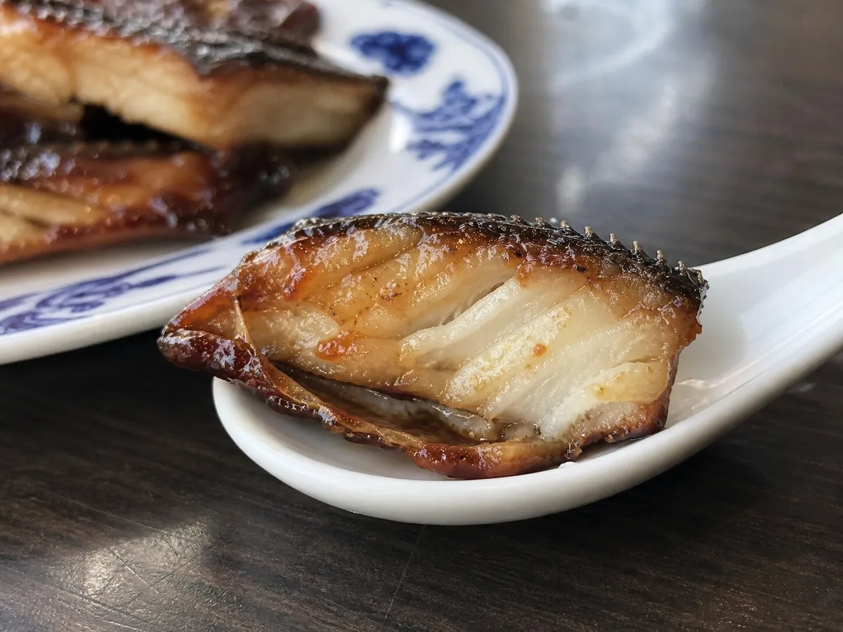 Close view of Shanghai smoked fish showing firm flaky fish interior and sweet-savory glaze