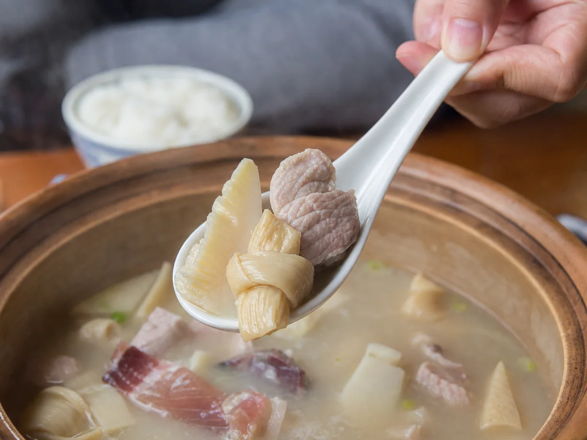 Soup ladle holding pork, bamboo shoot, and tofu-skin knot above Shanghai yanduxian