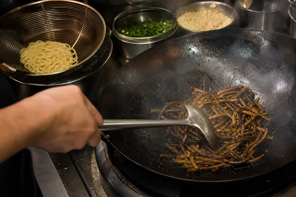 Cook stir-frying shredded eel for Shanghai eel noodles in a wok
