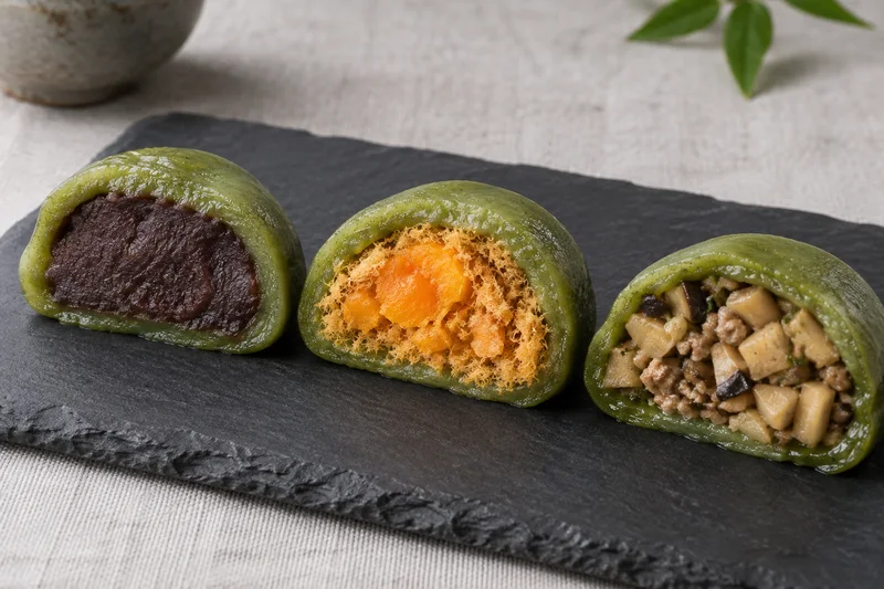 Cut Shanghai qingtuan showing red bean, salted egg yolk with pork floss, and savory bamboo shoot fillings
